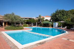 una grande piscina in un cortile con un resort di Hotel la Torre a Bari Sardo