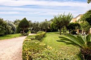einen Garten mit Bäumen und einer Feldstraße in der Unterkunft Hotel la Torre in Bari Sardo