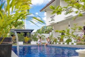 two people sitting in the swimming pool of a villa at Thistle Inn in Panglao Island
