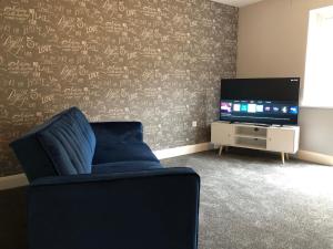 a living room with a blue chair and a television at Hill House - 5 Mins Merry Hill - Perfect for Contractors & Families in Brettell Lane