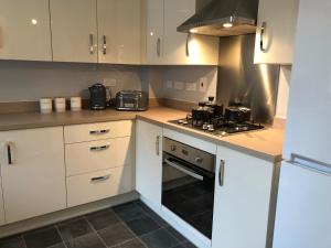 uma cozinha com armários brancos e um forno com placa de fogão em Hill House - 5 Mins Merry Hill - Perfect for Contractors & Families em Brettell Lane