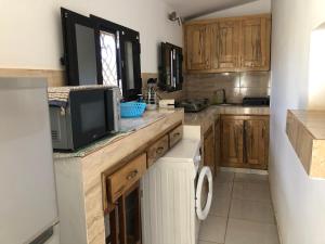 a kitchen with wooden cabinets and a tv on a counter at La Maison Aziz - Somone / Sénégal in Somone