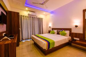 a bedroom with a large bed and a television at Treebo Trend Prince Palace in Mahabaleshwar