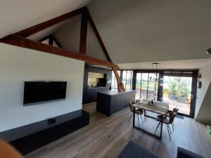 a large living room with a table and a tv at B&B Vierlingsbeek, Appartement Onder één dak en tuin-chalet in Vierlingsbeek