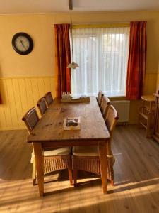 a dining room table with chairs and a clock on the wall at de Zandput 46 in Zoutelande +7 photos