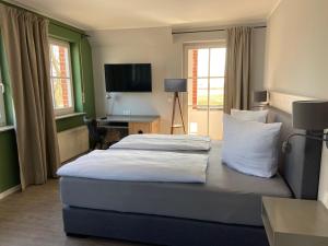 a bedroom with a bed and a desk and a television at Hotel & Gasthof Zur Linde in Middelhagen