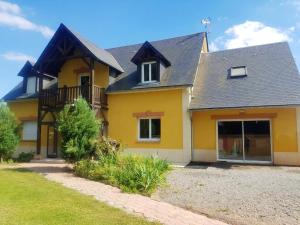 ein gelbes Haus mit schwarzem Dach in der Unterkunft Villa de 5 chambres avec piscine privee jacuzzi et jardin clos a Saint Clair d'Arcey in Bernay