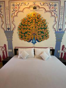 - une chambre avec un lit orné d'une grande peinture murale dans l'établissement Golden Peacock Heritage Home Stay, à Jaipur