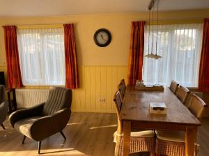 a dining room table with chairs and a clock on the wall at de Zandput 46 in Zoutelande