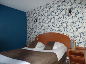 1 dormitorio con 2 camas y papel pintado con motivos florales en LOGIS Hôtel LES 3 MARCHANDS en Bressuire