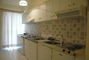 a kitchen with white cabinets and a sink at Tzovanna Studios in Loutra Edipsou
