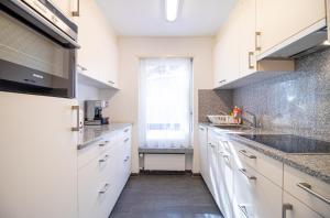 una cucina con armadietti bianchi e una finestra di Gentiana B2 by Arosa Holiday a Arosa