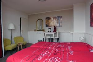 a bedroom with a red bed and a kitchen at Texelzon in Den Hoorn