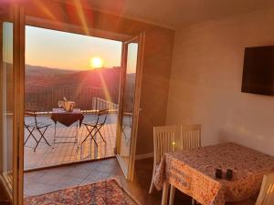 a room with a table and a balcony with the sunset at Apartmaji Aucin - Brda in Kojsko