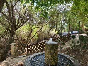 a fountain in a garden with a fence and trees at Molino Sauco - Hammam in Puebla de Don Fadrique