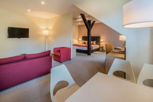 Best Western Hotel Schlossmühle Quedlinburg في كفيدلينبورغ: غرفة معيشة مع أريكة حمراء وغرفة نوم