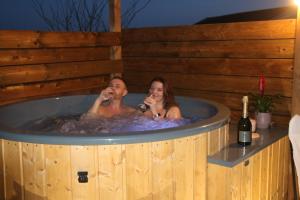 Ein Mann und eine Frau in einer Whirlpool-Badewanne in der Unterkunft LA ROULOTTE DES AMISH & Bain Nordique à Remous Jacuzzi in Mattexey