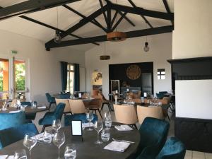 a dining room with tables and chairs and a screen at LOGIS H&ocirc;tel LES 3 MARCHANDS in Bressuire