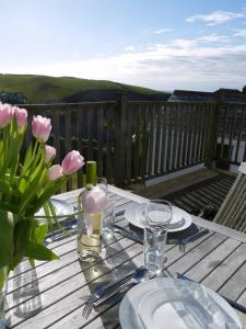 a table with plates and glasses and flowers on a deck at Bay View, Port Isaac in Port Isaac