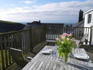 a wooden table with a vase of flowers on a deck at Bay View, Port Isaac in Port Isaac