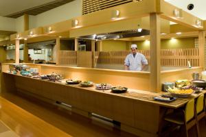 a man standing behind a buffet line with food at Yumetsuzuri in Omaki