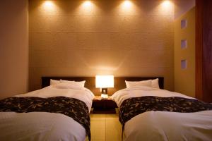 2 camas en una habitación de hotel con una lámpara entre ellas en Yumetsuzuri, en Omaki