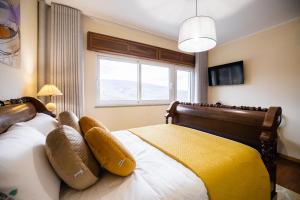 a bedroom with a bed with a yellow blanket on it at Green House - Douro in Peso da Régua