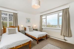 two beds in a room with two windows at Boskenna, Tintagel in Forrabury