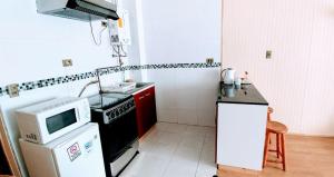 a small kitchen with a stove and a microwave at Furnished Apartment Cabaas del Profe in Puerto Montt