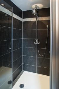 a bathroom with a shower with black tiles at B&B Kaai 16 in Halle