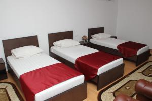 a room with three beds with red and white sheets at Hotel Royal 2 in Urziceni