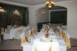 een eetkamer met witte tafels en stoelen bij Hotel Royal 2 in Urziceni