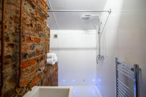 un bagno con doccia accanto a un muro di mattoni di Rooms by Green Room a Leeds