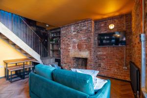 a living room with a blue couch and a brick wall at Rooms by Green Room in Leeds