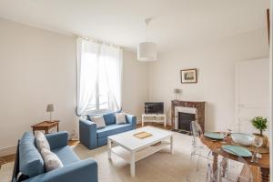 a living room with a blue couch and a table at LE SEIZE - Appartement spacieux au cœur d'un quartier calme de Rennes in Rennes