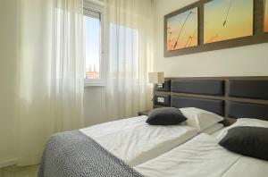 a bedroom with a bed with white sheets and a window at PRIMA Inn Ferienwohnungen Seetor Residenz in Neuruppin