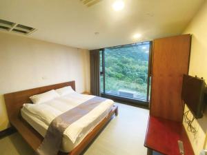 una camera da letto con un letto e una grande finestra di 礁溪景觀溫泉會館 a Jiaoxi