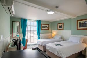 um quarto com duas camas e uma mesa e uma janela em The Clarendon Hotel em Deal