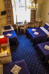 um quarto de hotel com três camas e uma mesa em Blades Hotel em Londres