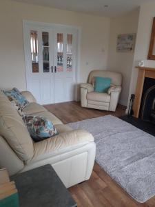 a living room with two white couches and a fireplace at 10 Clara Meadows in Culdaff