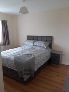 a bedroom with a bed and a wooden floor at 10 Clara Meadows in Culdaff