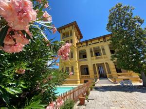 ein großes gelbes Gebäude mit einem Pool und Blumen in der Unterkunft Villa Moorings in Barga