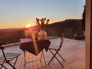 a table and chairs with a vase and flowers on a patio at Apartmaji Aucin - Brda in Kojsko +22 photos