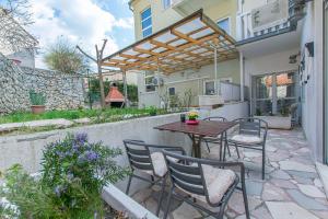 eine Terrasse mit einem Tisch, Stühlen und einem Zaun in der Unterkunft Apartments Clarus Mare in Duće