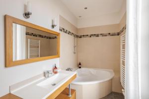 a bathroom with a tub and a sink and a mirror at LE SEIZE - Appartement spacieux au cœur d'un quartier calme de Rennes in Rennes