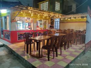 un restaurant avec des tables en bois, des chaises et des lumières dans l'établissement KASAHARA - HOMESTAY, à Bolpur