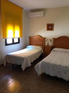 a bedroom with two beds and two windows at Casa Rural las Escuelas II in Hoyo de Pinares