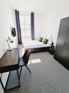 Habitación con cama, escritorio y silla. en Best Boarding House, en Hanau am Main