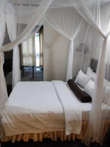 a bedroom with a white bed with a canopy at Lake Kariba Inns in Siavonga