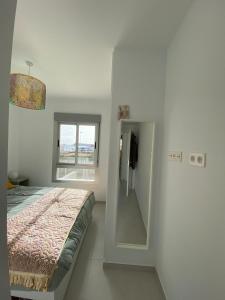 ein weißes Zimmer mit einem Bett und einem Spiegel in der Unterkunft Casa Kelly in Puerto de Mazarrón